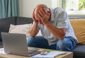 man struggles with finances in front of laptop